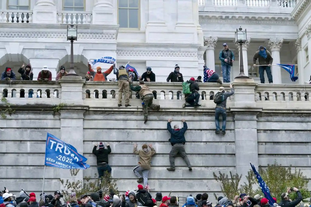 Supporters of then President Donald Trump climb the west wall of the the US Capitol in Washington on 6 January 2021 as part of an effort to overturn the election results.